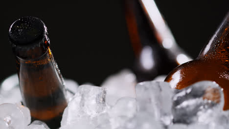 Primer-Plano-De-Botellas-De-Vidrio-De-Cerveza-Fría-O-Refrescos-Enfriándose-En-Un-Cubo-Lleno-De-Hielo-Sobre-Fondo-Negro-2